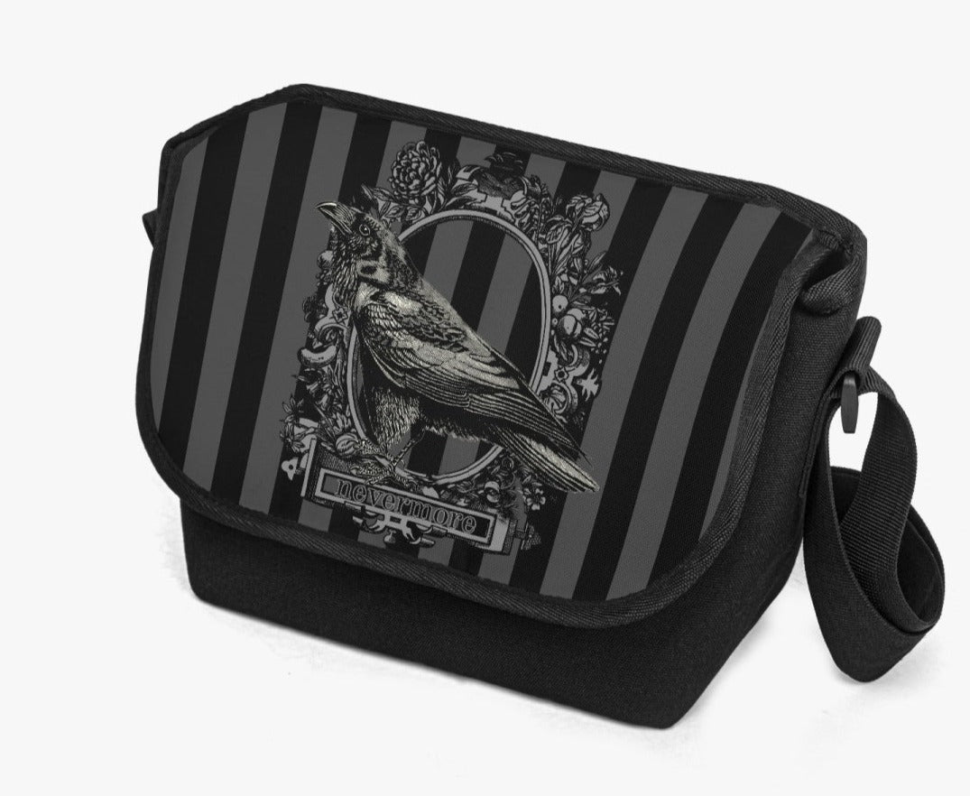 image shows a padded messanger style bag with wide strap.  The printed front flap features a gothic grey and black stripe background with a raven motif  in black