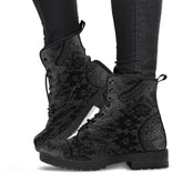 image shows a black and grey lace up combat style boot with a black lace print on a grey background. The sole and laces of the boots are black and overall the boots have a gothic vibe.