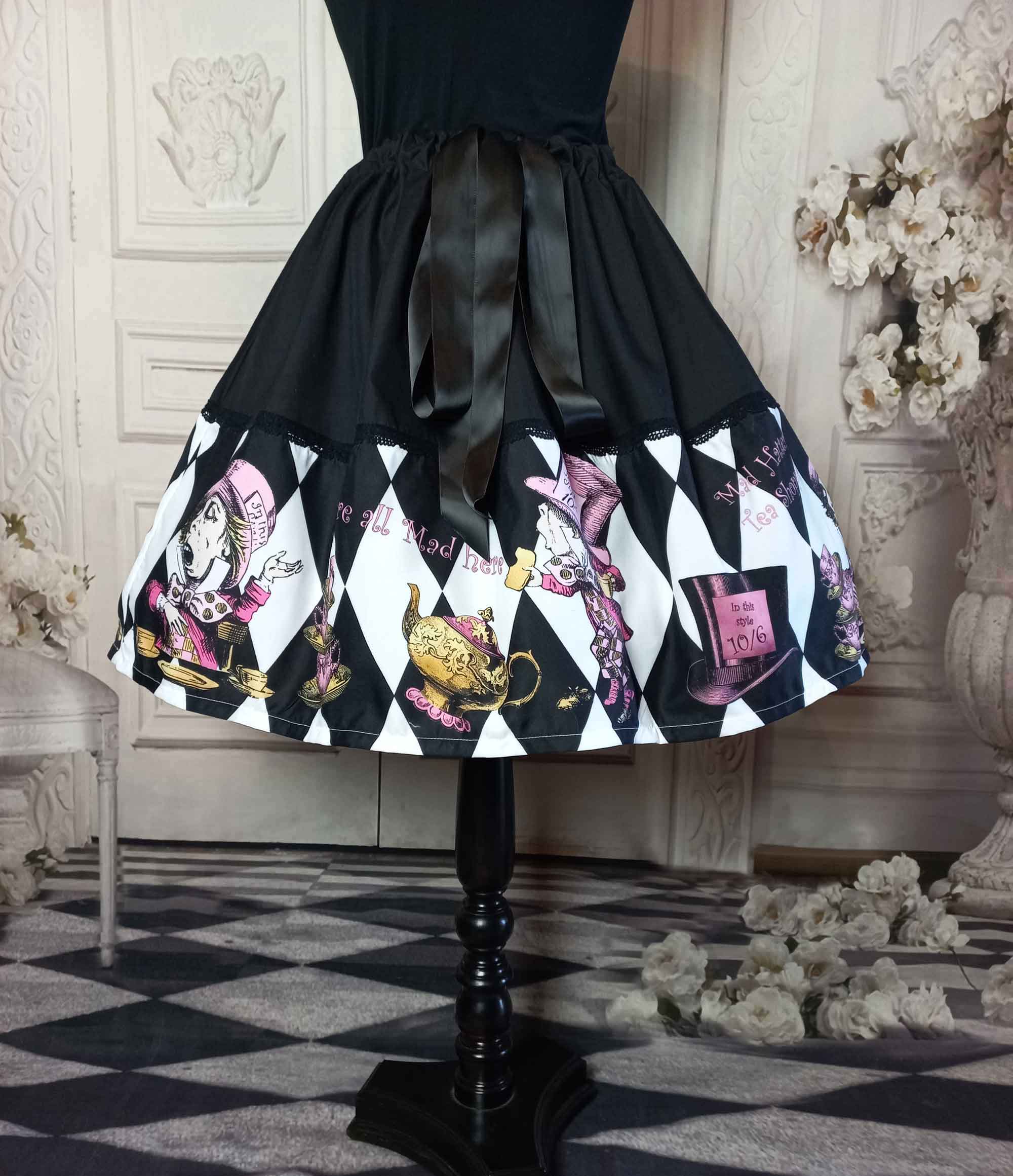 alice in wonderland mad hatter tea party full fifties style skirt. The skirt features the mad hatter, teacups, teapots and top hats in pinks and golds on a black and white diamond print background. The upper half of the skirt is black with a decorative ribbon tie at the fully adjustable waist