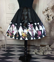 alice in wonderland mad hatter tea party full fifties style skirt. The skirt features the mad hatter, teacups, teapots and top hats in pinks and golds on a black and white diamond print background. The upper half of the skirt is black with a decorative ribbon tie at the fully adjustable waist
