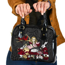 Load image into Gallery viewer, Alice in wonderland black shoulder handbag featuring Alice holding the baby pig watched by the white rabbit and cheshire cat.  The bag has a black lace print background and the characters are in red, white and gold. The bag has black handles.
