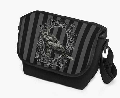 image shows a padded messanger style bag with wide strap.  The printed front flap features a gothic grey and black stripe background with a raven motif  in black 