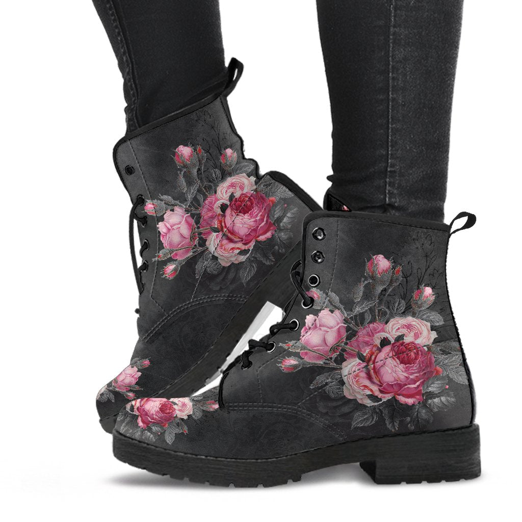 image shows gothic lace up combat boots with  black soles and black laces just above ankle length.  The boots feature a print of pink and grey roses on a grey grungy background